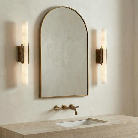 Delya LED Wall Sconce 22", Antique Brass and Alabaster linear Wall Sconce in a Modern Bathroom with an arched mirror and travertine vanity.