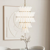 Brielle 13 Light Chandelier finished in  White Art Glass with Aged Brass is shown in a bright dining area in front of modern art. 