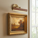 Jarrett LED Picture Light 12", Aged Brass and Cognac Leather linear picture light in a Transitional Living Room with an ornate gold framed painting.