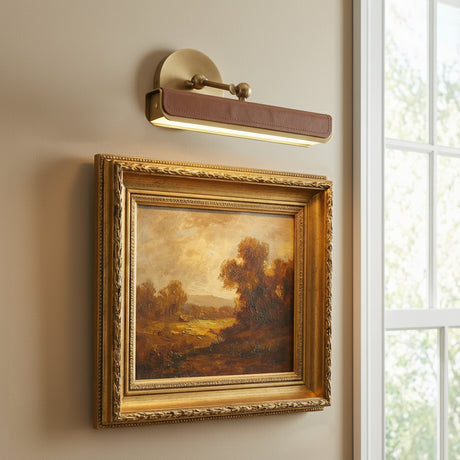 Jarrett LED Picture Light 12", Aged Brass and Cognac Leather linear picture light in a Transitional Living Room with an ornate gold framed painting.