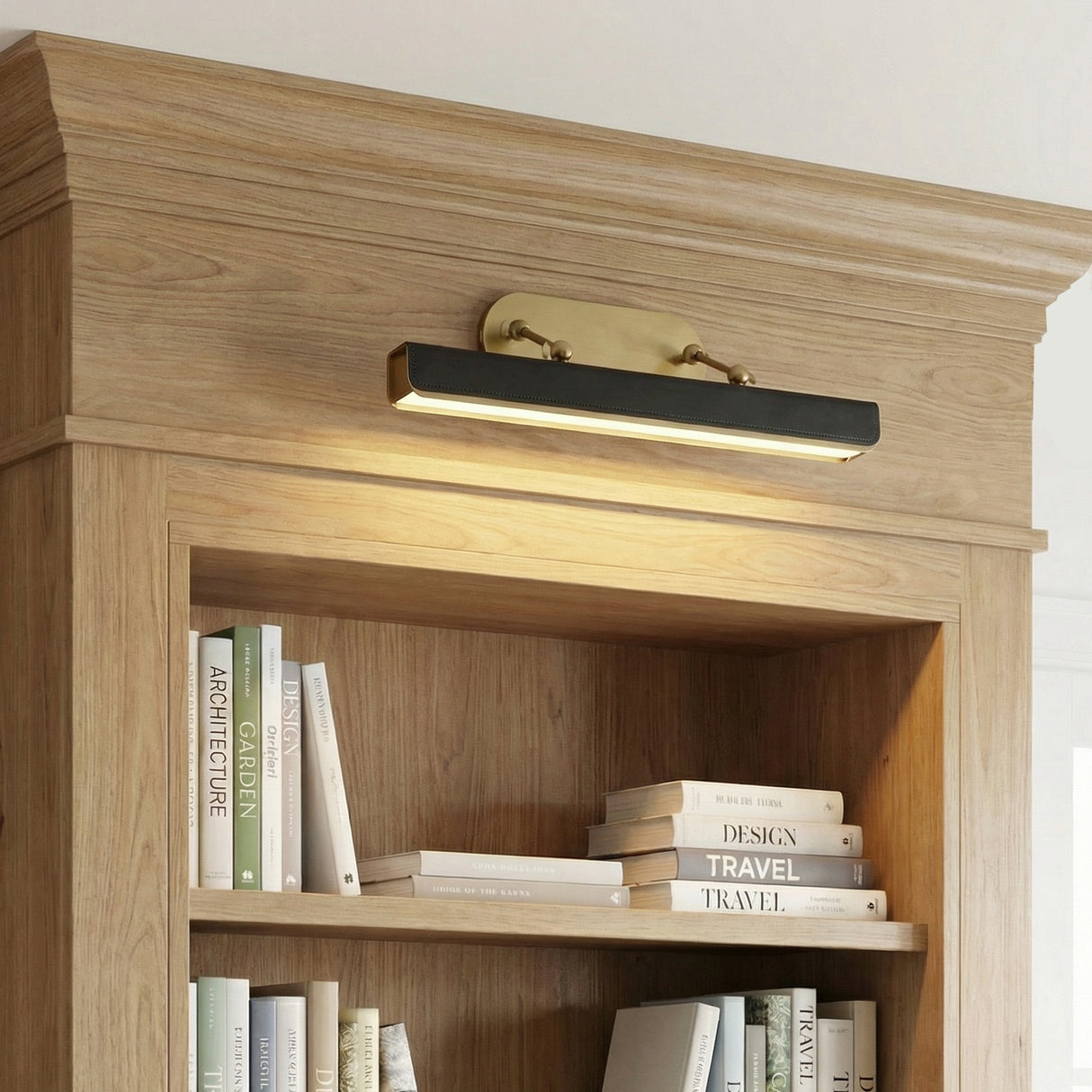 Jarrett LED Picture Light 20", Aged Brass and Tuxedo Leather styled in a Modern entryway with wood shelving.