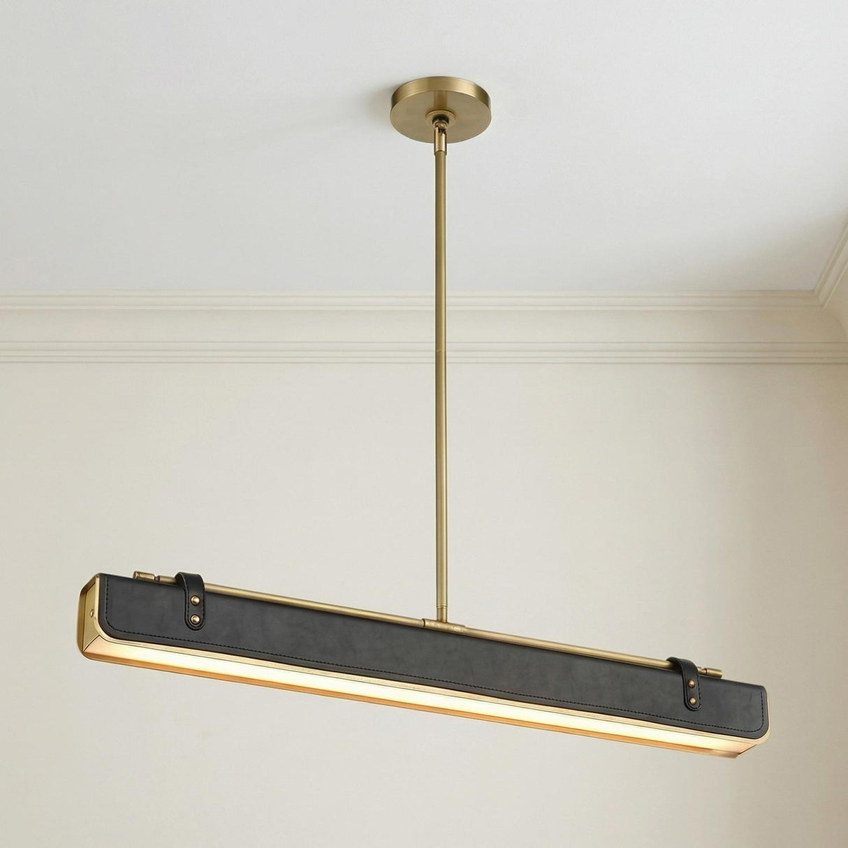 Jarrett LED Linear Pendant 31", Aged Brass and Tuxedo Leather linear pendant in a Contemporary Dining Room with a sleek dining table.