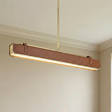 Jarrett LED Linear Pendant 31", Aged Brass and Cognac Leather linear Pendant in a Transitional Dining Room with crown molding.