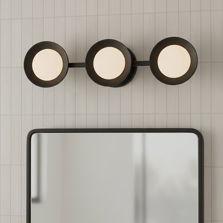 Elon 3 Light LED Vanity 24, Matte Black and Opal Glass - Three circular lights with opal glass are mounted horizontally on a matte black bar against a white tiled wall, above a black-framed mirror.