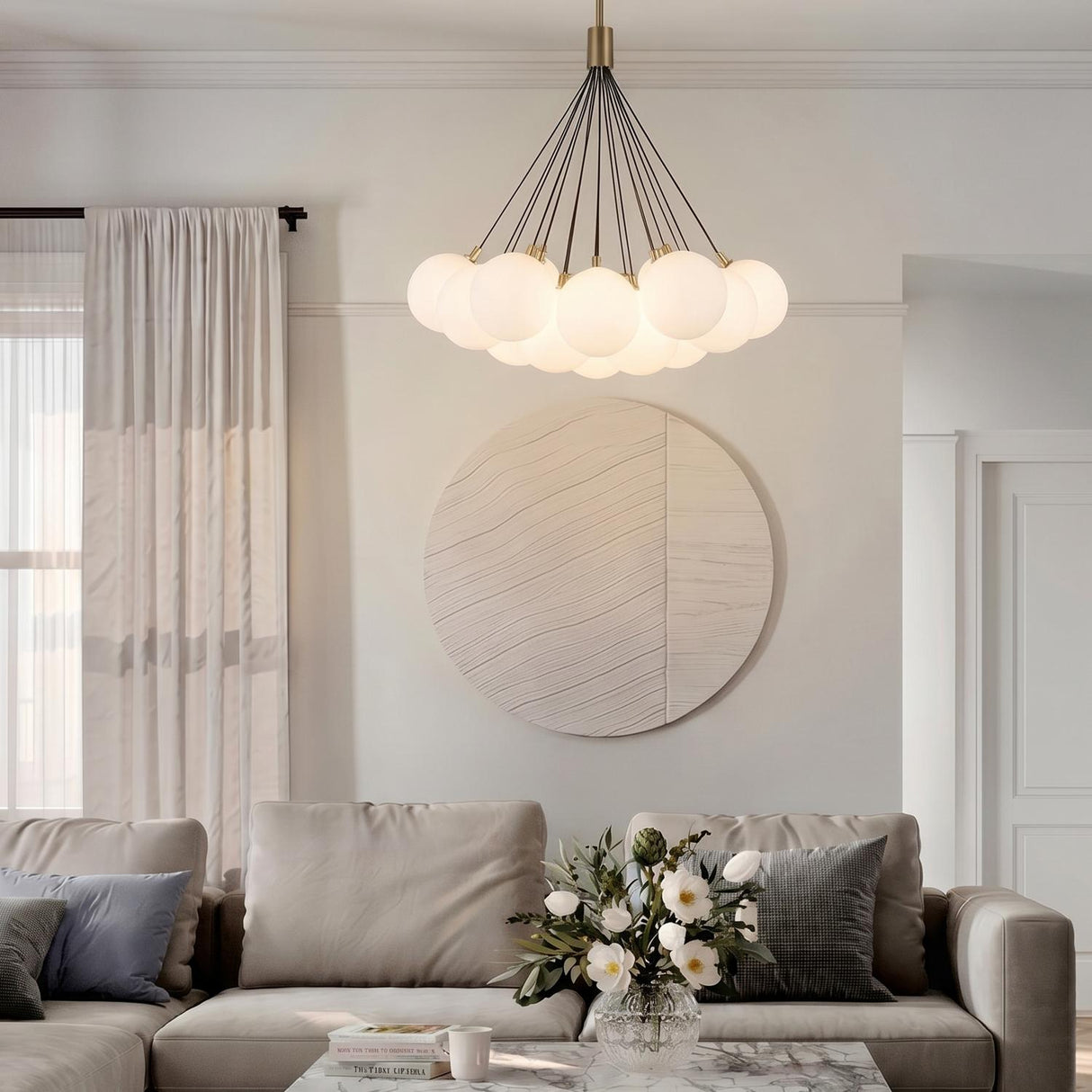 A contemporary living room featuring the Soren 19 Light LED Chandelier 28", Brushed Brass and Opal Glass centered above a marble coffee table and beige sectional.