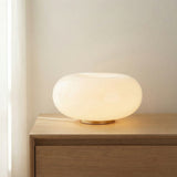 Otto LED Table Lamp 13, Aged Brass and Opal Glass in a Modern Bedroom on a wood nightstand.