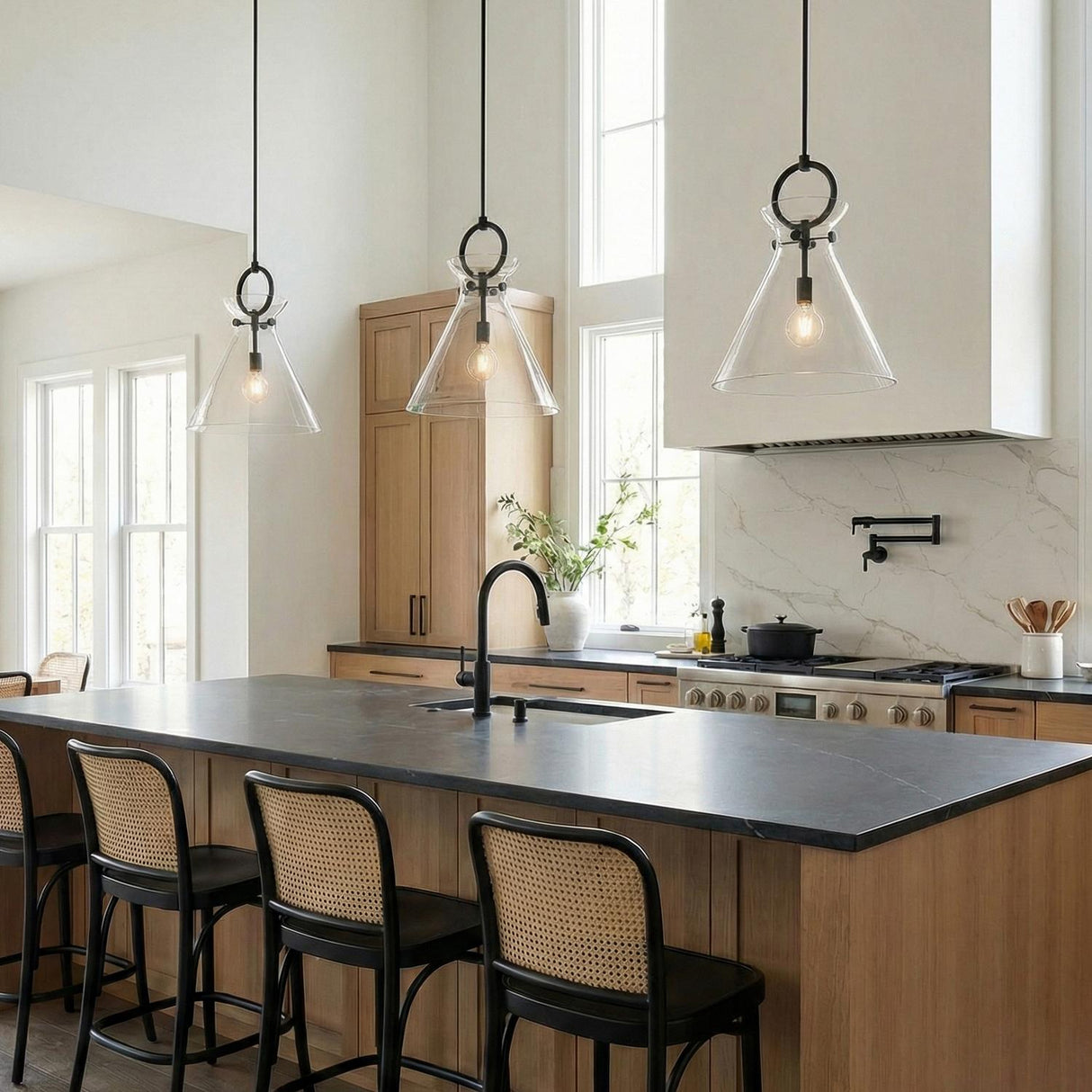 Aris Matte Black and Clear Glass geometric pendant in a Modern Farmhouse Kitchen with cane-back barstools and a black island.