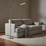 Linden LED Floor Lamp 55", Aged Brass - A brass floor lamp illuminating a gray sofa