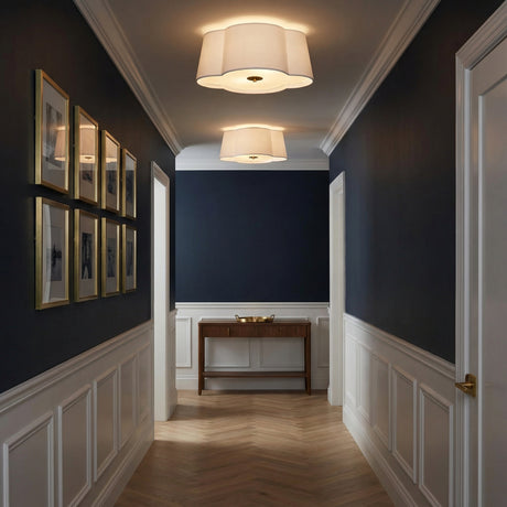 White and Brass scalloped flush mount in a Transitional Entryway with dark blue wainscoted walls and gold frames.