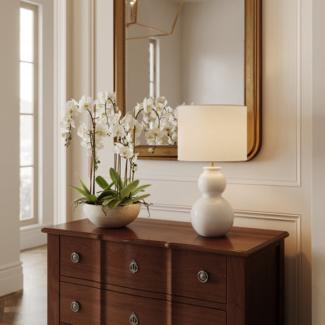 Truett Table Lamp 27" tall, in Glossy White with white linen shade is shown on a classic entry table next to an orchid plant.