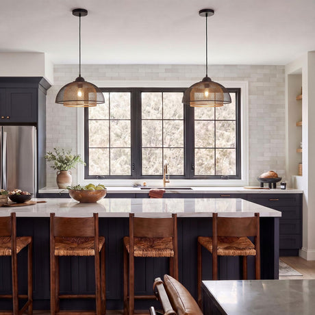 A modern kitchen with two Tate LED Pendant 16-inch Matte Black and Brass fixtures over a white marble island with navy cabinets and a white subway tile backsplash.