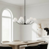Wallace 6 Light Chandelier 38, Matte Black - A matte black chandelier with white conical shades hangs above a light wood dining table with upholstered chairs, with a large arched window in the background and abstract art on the wall.