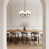 Anise 5 Light 30" wide Chandelier 30", Matte Black with white fabric shades, is shown above a dining table with modern chairs and seating for 8