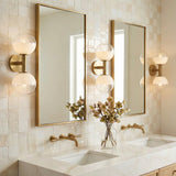 Merrick 2 Light Wall Sconce 15", Modern Brass styled in a Modern Bathroom with tiled walls and marble countertop.