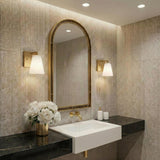 Margot Wall Sconce 8", Satin Brass geometric Wall Sconce in a Contemporary Bathroom with a black marble counter and arched mirror.