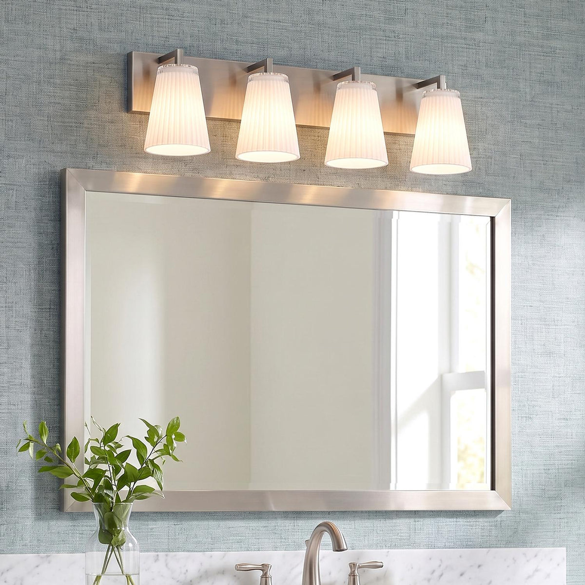 A transitional bathroom featuring the Margot 4 Light Vanity, Brushed Nickel light fixture with ribbed glass shades mounted over a matching framed mirror and marble countertop.