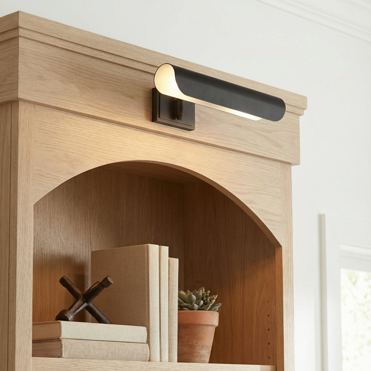 Denton Picture Light 13", Aged Iron linear wall sconce in a Transitional Living Room with a light oak built-in bookshelf.