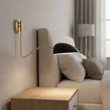 Camden Adjustable Wall Sconce, Matte Black - A matte black wall sconce with a brass arm extends over a bed with neutral bedding and pillows.