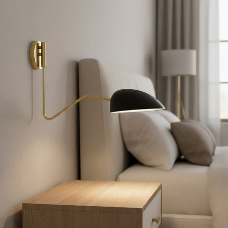 Camden Adjustable Wall Sconce, Matte Black - A matte black wall sconce with a brass arm extends over a bed with neutral bedding and pillows.
