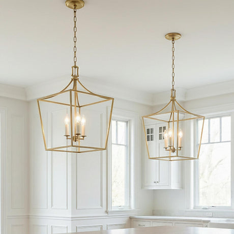 A transitional kitchen featuring two Grayden Medium Lantern Pendant 13", Modern Brass fixtures over the island set against white wall molding and white cabinets.