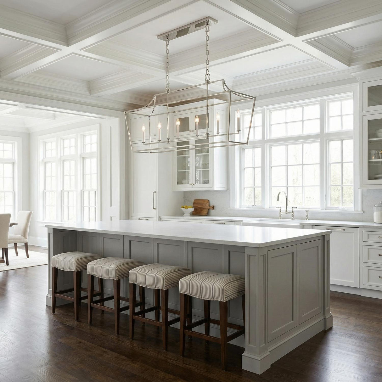 A transitional kitchen features the Grayden Linear Lantern 48", Polished Nickel suspended over a gray island with white marble countertops under a white coffered ceiling.