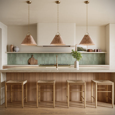 Three Paloma 22" Pendant lights in Modern Brass and Rattan are hung above a kitchen island with seating for four, in an organic modern kitchen with green backsplash tiles and open shelving.