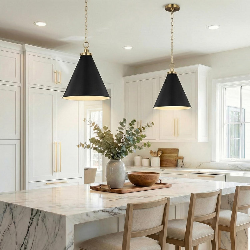 A transitional kitchen features two Classon Medium Pendant 16", Matte Black and Modern Brass pendants over a white marble waterfall island surrounded by white shaker cabinets.