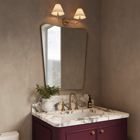 Harlow Double Wall Sconce, Modern Brass with Rattan above a burgundy single vanity with a curvy mirror