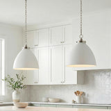 A transitional kitchen features two Rodney Large Pendant 18", Matte White and Polished Nickel fixtures over the island, alongside white shaker cabinets and a glossy tile backsplash.