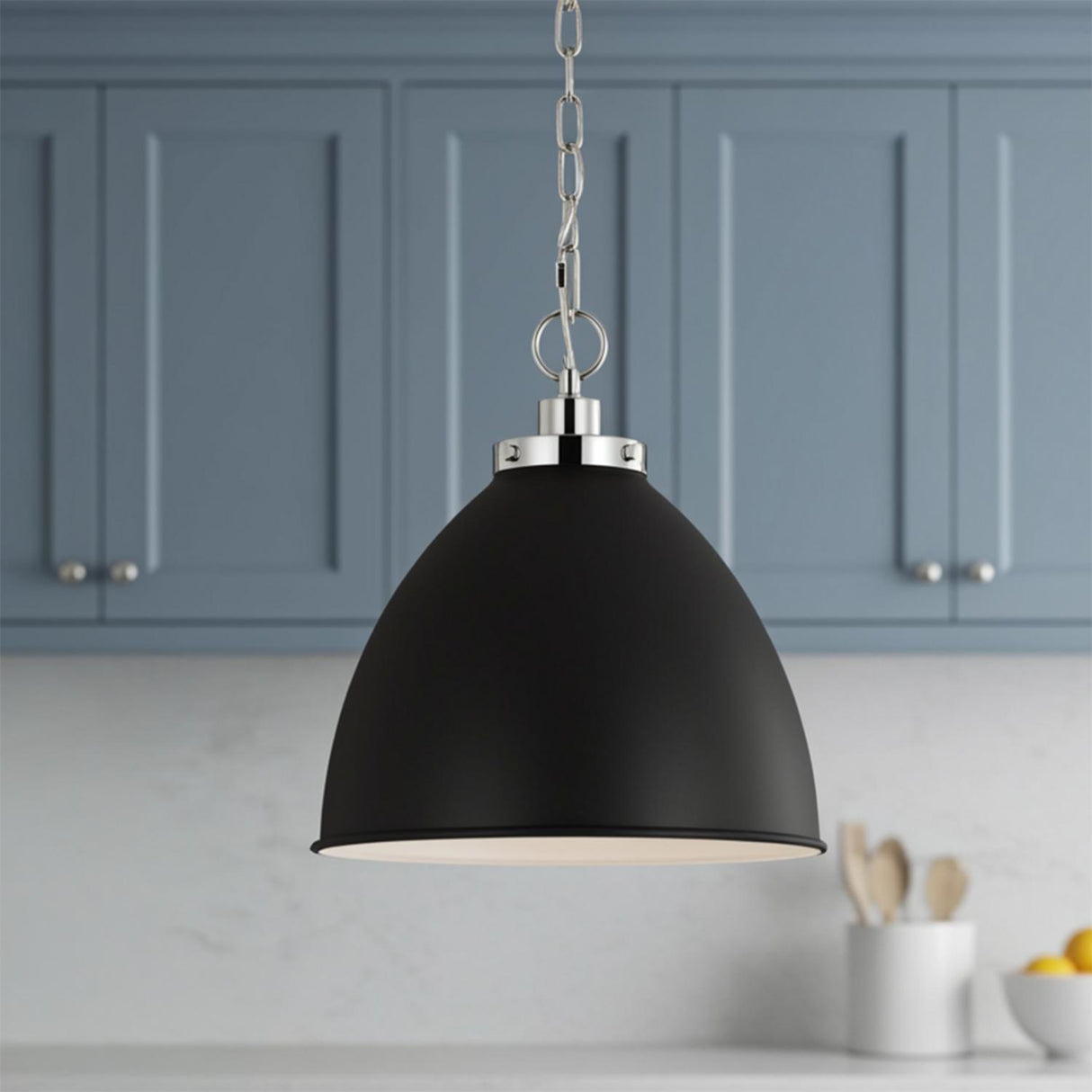 A transitional kitchen features the Rodney Medium Pendant 16-inch, Matte Black and Polished Nickel hanging over the sink in front of blue-gray cabinets and white marble backsplash.