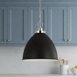 A transitional kitchen features the Rodney Medium Pendant 16-inch, Matte Black and Polished Nickel hanging over the sink in front of blue-gray cabinets and white marble backsplash.