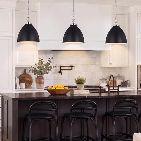 A transitional kitchen features three Rodney Large Pendants in Matte Black and Polished Nickel hanging over a dark island with black counter stools.