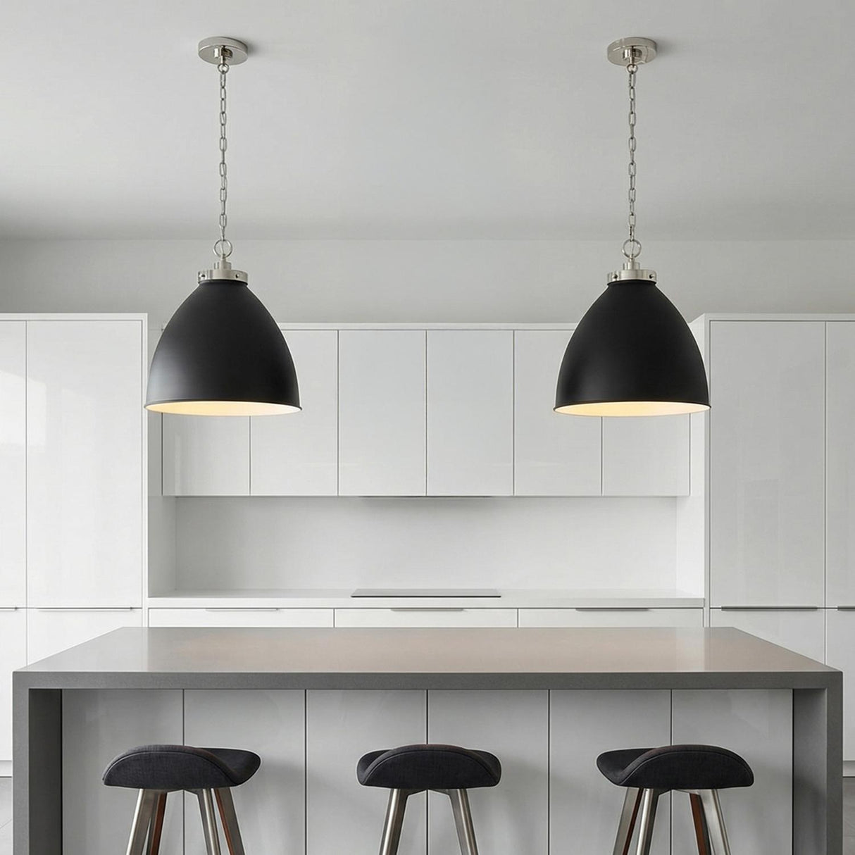A minimalist kitchen featuring two Rodney Large Pendant 18", Matte Black and Polished Nickel fixtures over a grey waterfall island set against white flat-panel cabinets.