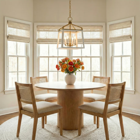 Fillmore Medium Lantern Pendant 13", Matte White and Modern Brass geometric Pendant in a Transitional Dining Room with a light wood pedestal table and cane chairs.