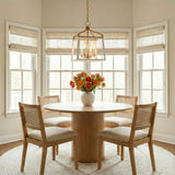 Fillmore Matte White and Modern Brass geometric lantern pendant in a Transitional Dining Room with an oak pedestal table and cane chairs.