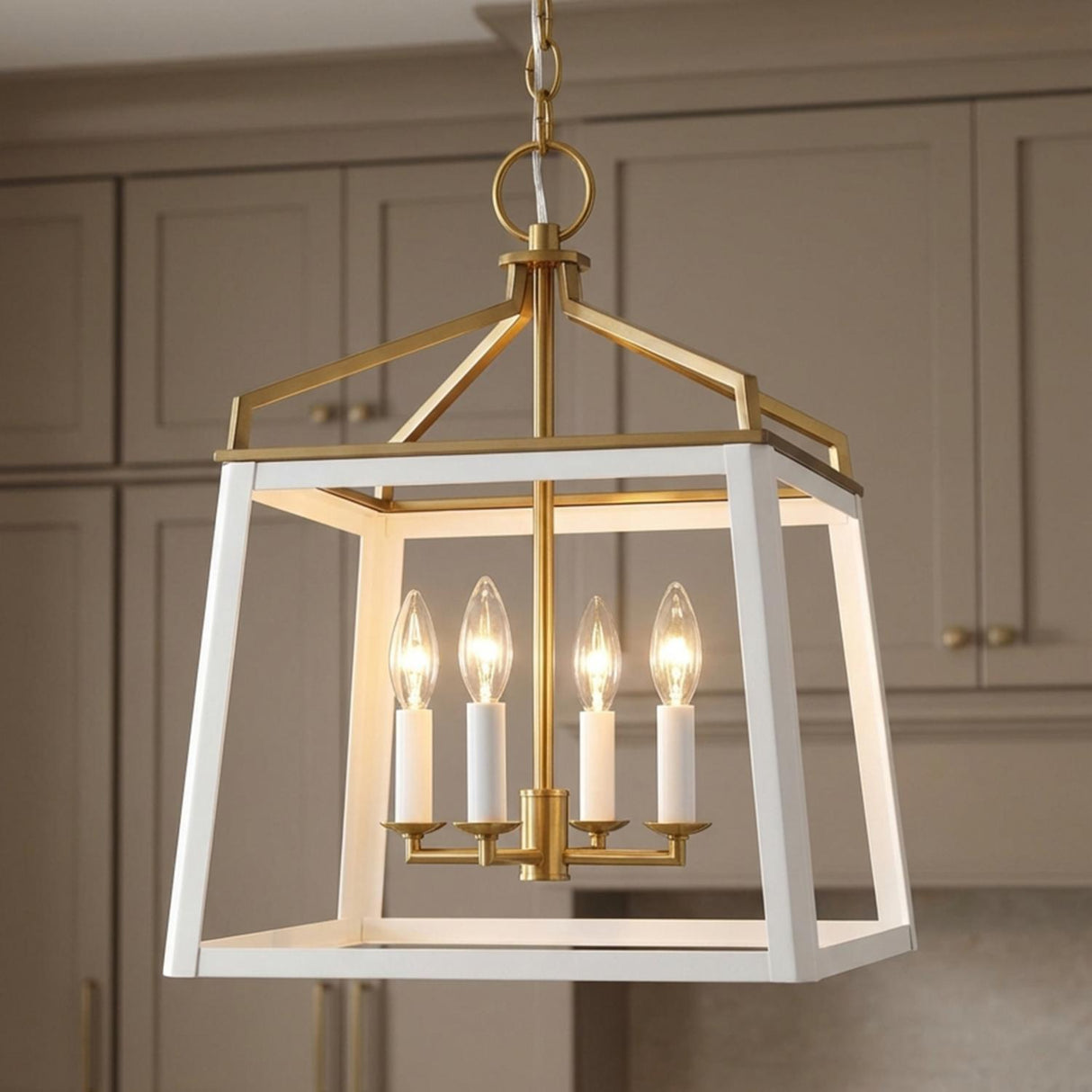 A transitional kitchen features a Fillmore Medium Lantern Pendant 13", Matte White and Modern Brass over an island with taupe shaker-style cabinetry in the background.