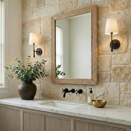 Emerson Wall Sconce 14", Aged Iron linear Wall Sconce in a Modern Farmhouse Bathroom with a stone wall and jute mirror.