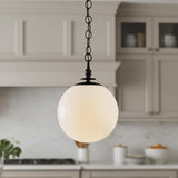 A transitional kitchen featuring an Emerson Large Pendant 14", Aged Iron with a white glass globe over the island, gray shaker cabinets, and a marble backsplash.