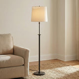 Emerson Floor Lamp, Aged Iron linear Floor Lamp in a Transitional Living Room with a textured beige armchair and jute rug.