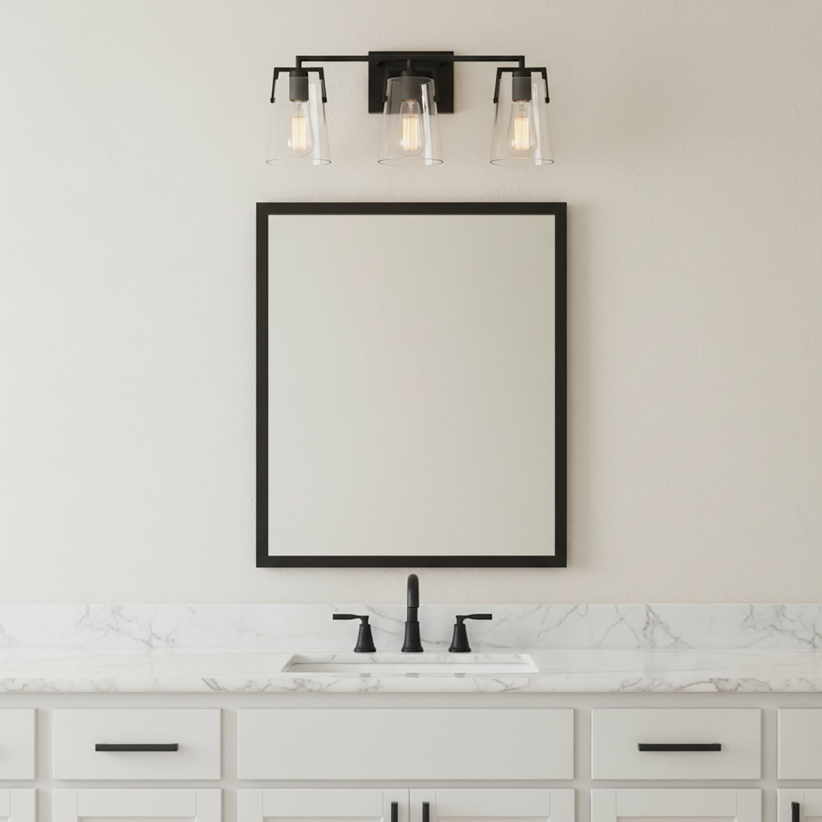 Glyn 3 Light 24" wide Vanity Light, Matte Black and clear glass, shown above a single sink and mirror in a neutral designed bathroom.