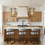 A transitional kitchen features two Rawlin Medium Lantern Pendants in matte black and brushed brass over the island with a white waterfall countertop and light wood cabinetry.