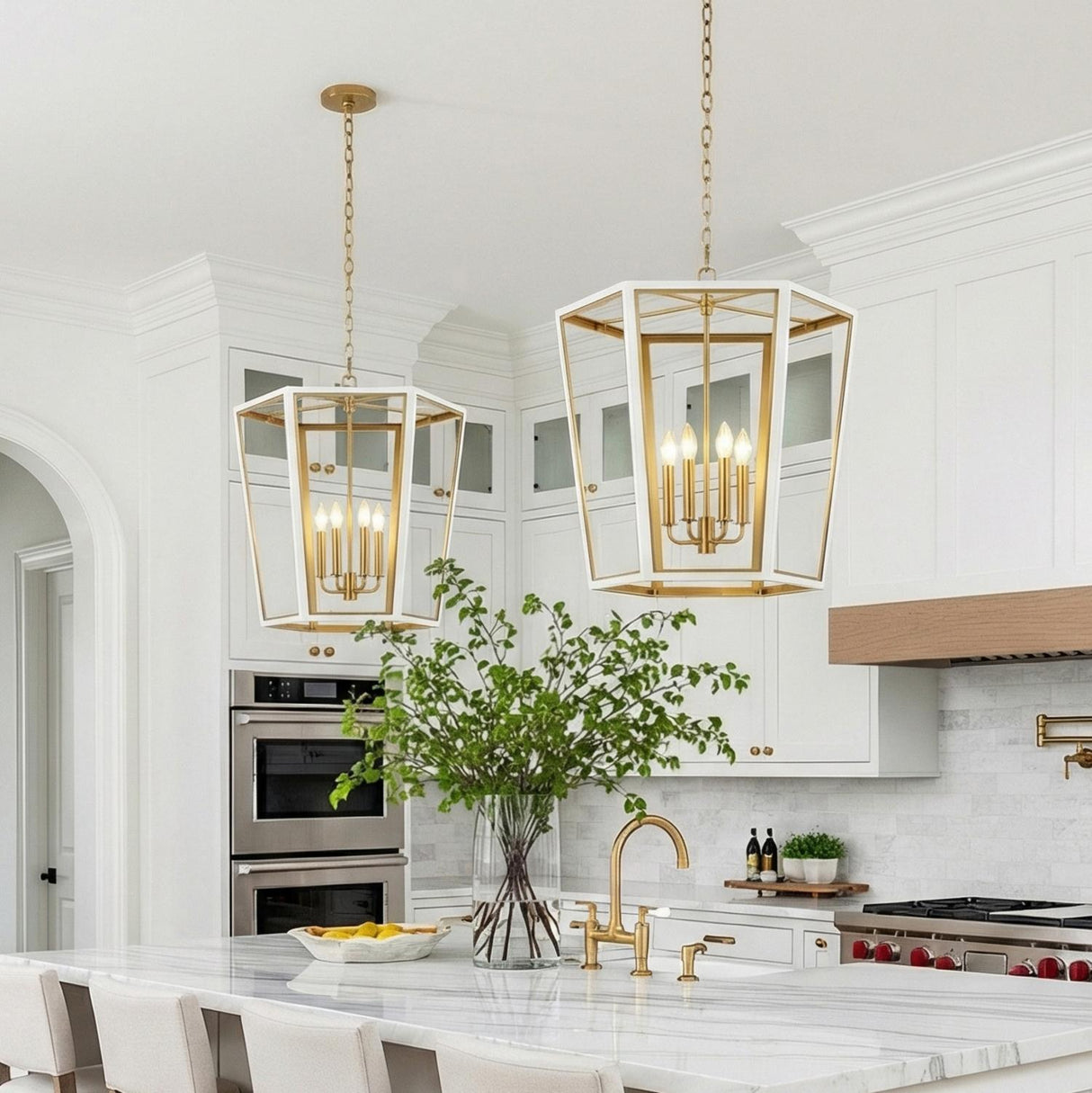 A transitional kitchen features two Rawlin Medium Lantern Pendant 21", Matte White and Brushed Brass fixtures over a marble island with white cabinetry and a matching backsplash.