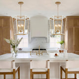 A transitional kitchen featuring two Rawlin Medium Lantern Pendants in matte white and brushed brass over a white marble island with natural wood cabinetry.