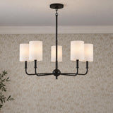 A transitional dining room features the Remington 5 Light Chandelier 26", Matte Black with white fabric shades suspended against floral wallpaper and crown molding.