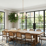 A transitional dining room featuring the Remington 6 Light Linear Chandelier 44", Satin Brass over a long oak table and rattan chairs in front of black-framed windows.