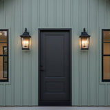 Dark gray door with two black Pembroke Medium Outdoor Wall Lights, 23" tall, on a dusty green house.