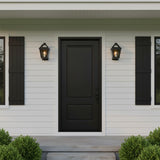 Fairmont Extra Small Outdoor Wall Light in Textured Black - Two black outdoor wall lights flank a black front door on a white-paneled house with black shutters and green bushes.
