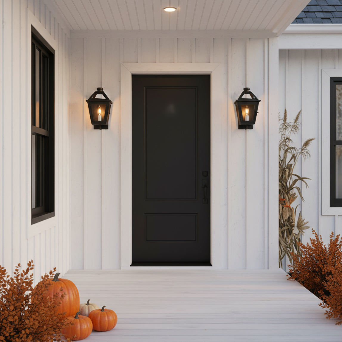 Fairmont Extra Small Outdoor Wall Light 13" in Textured Black - Two black outdoor wall lights flank a black door on a white farmhouse-style porch with pumpkins and autumn foliage.
