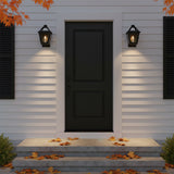 Fairmont Extra Small Outdoor Wall Light 13 - Two black lanterns flank a black front door with white siding and fallen autumn leaves on the steps.