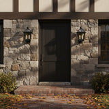 Fairmont Small Outdoor Wall Light - Two black lanterns flanking a dark door on a stone-clad exterior with autumn leaves.